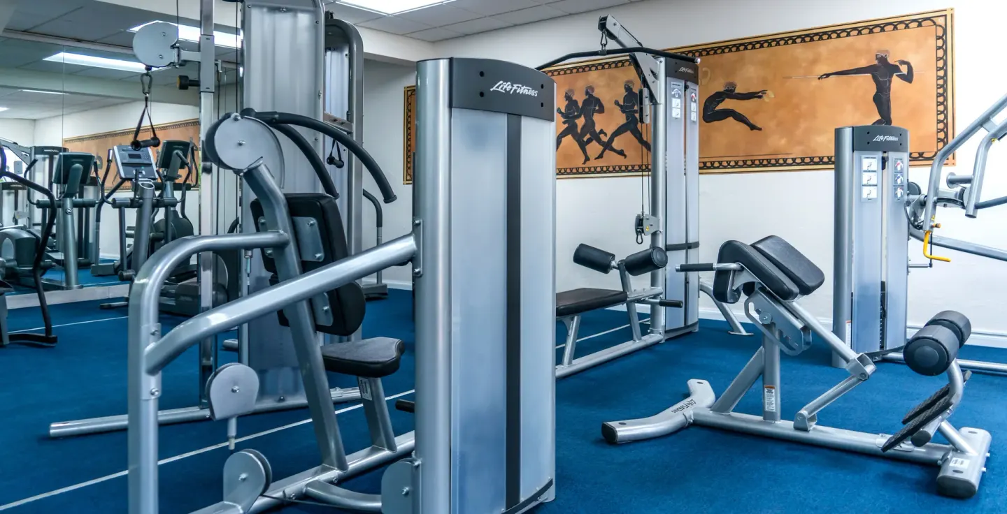 Fitness room with exercise machines and blue flooring at Coral Reef Club.