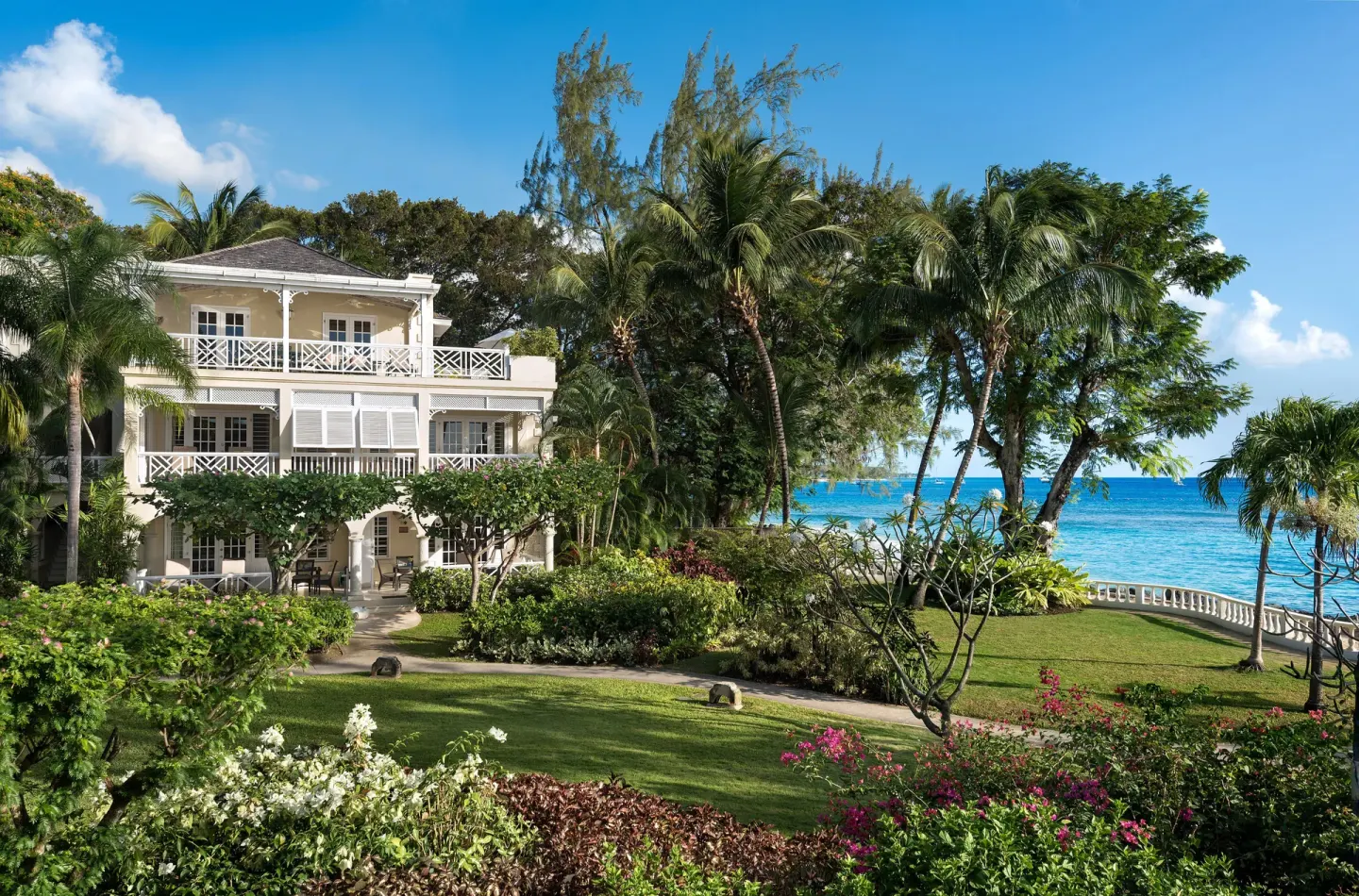 A white resort building stands among gardens and palms at Coral Reef Club.
