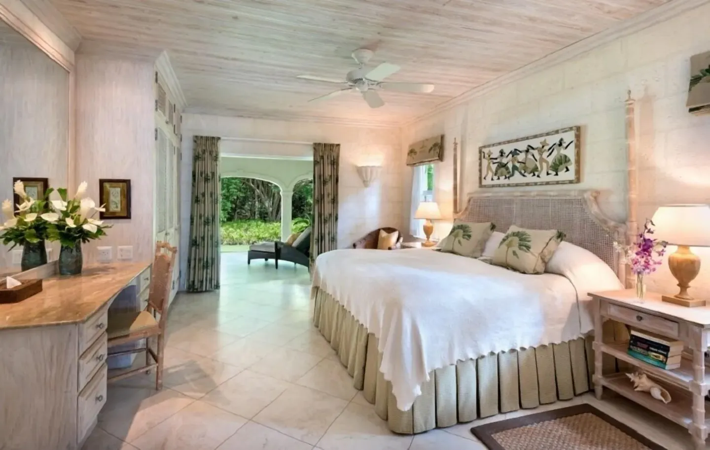 Guest room with a large bed, writing desk, and garden-facing patio at Coral Reef Club.