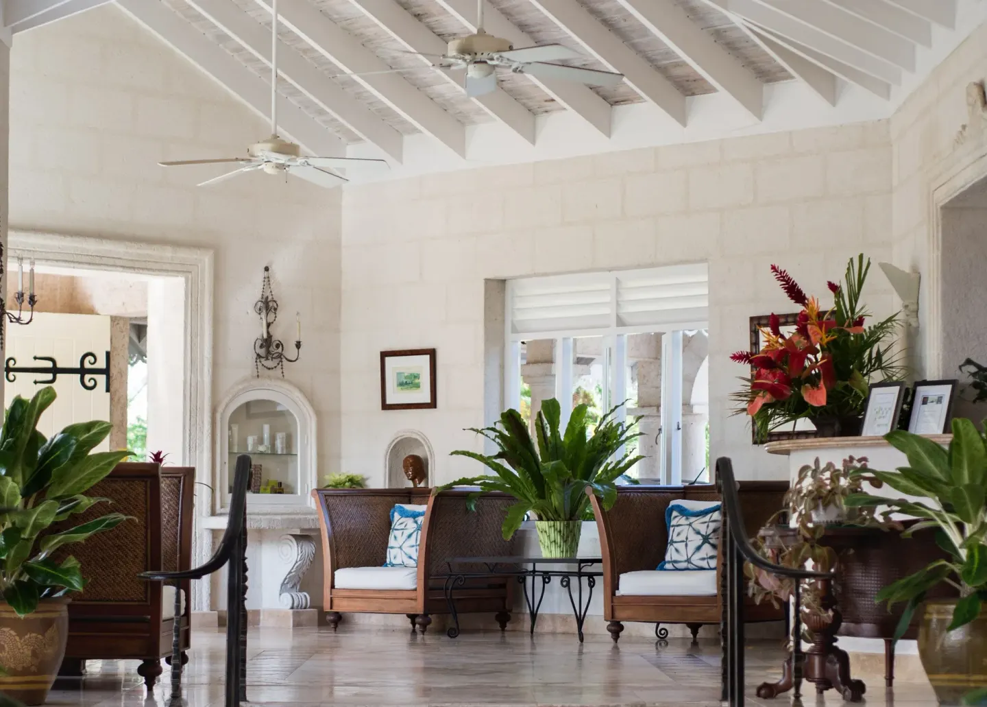 Lobby seating with plants, white beams, and wicker chairs at Coral Reef Club.