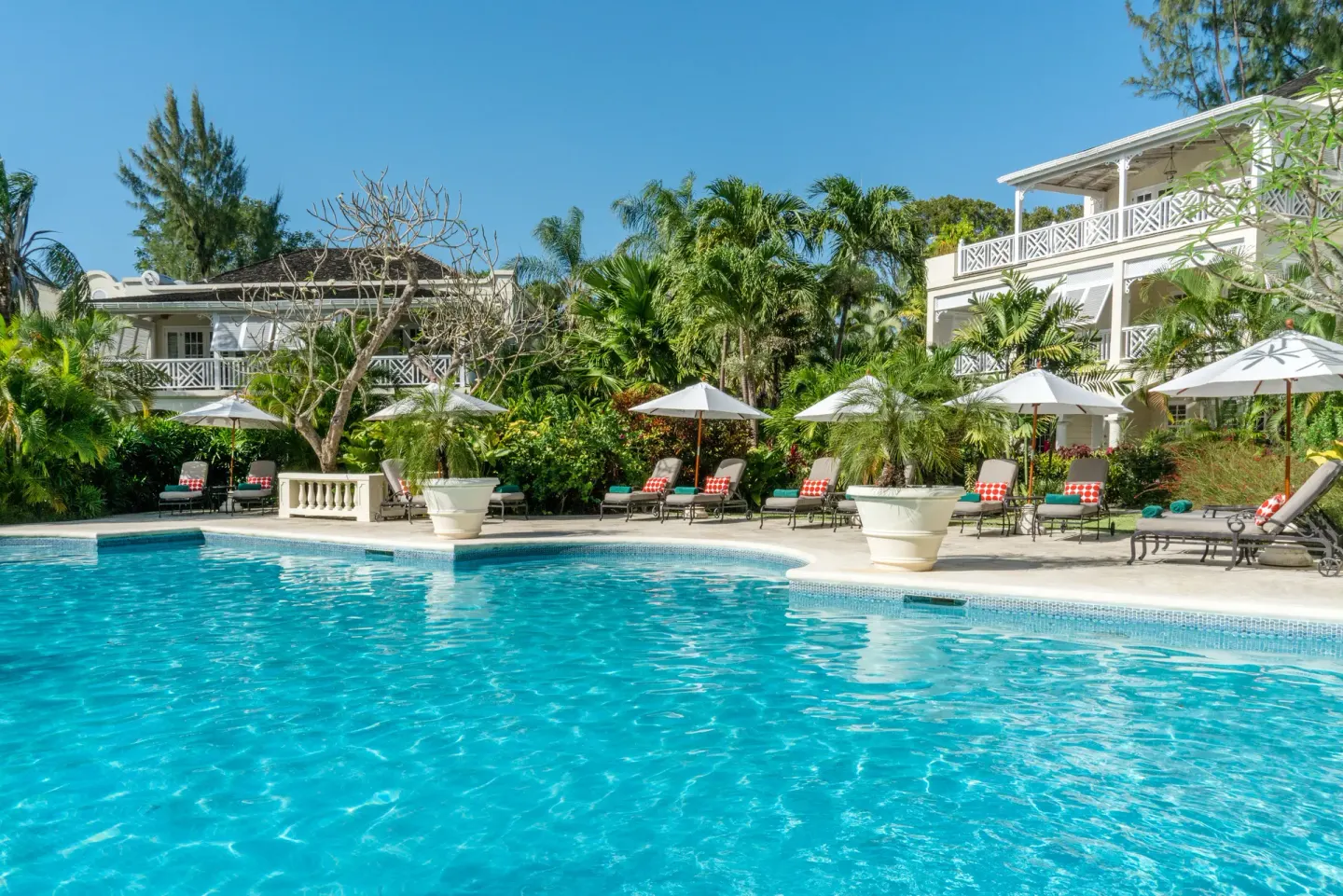 Sun loungers and white umbrellas line the resort pool at Coral Reef Club.
