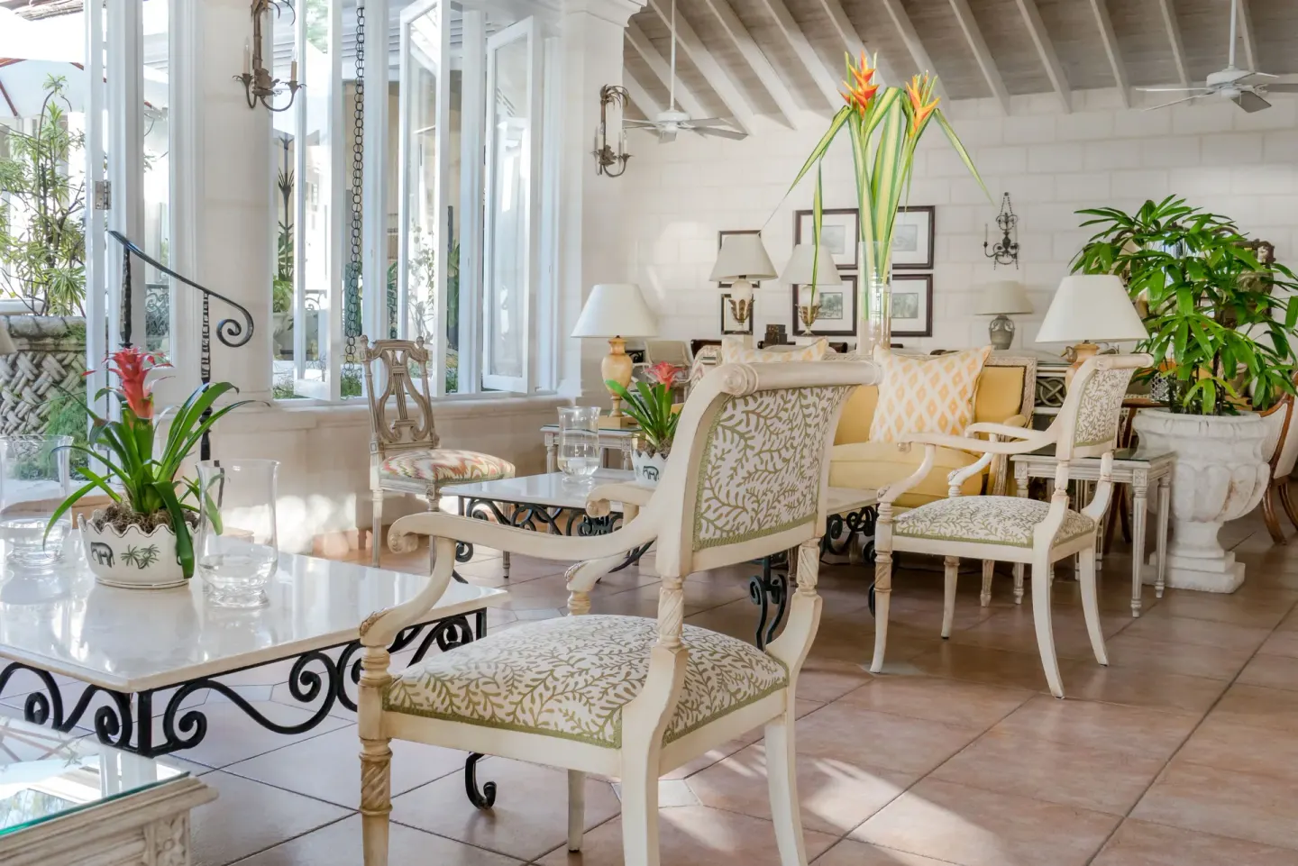 Sunlit lounge seating with white chairs and tropical flowers at Coral Reef Club.