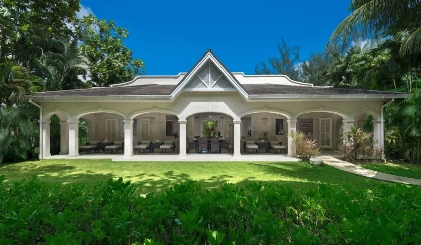 White villa exterior with arched veranda and lawn at Coral Reef Club.