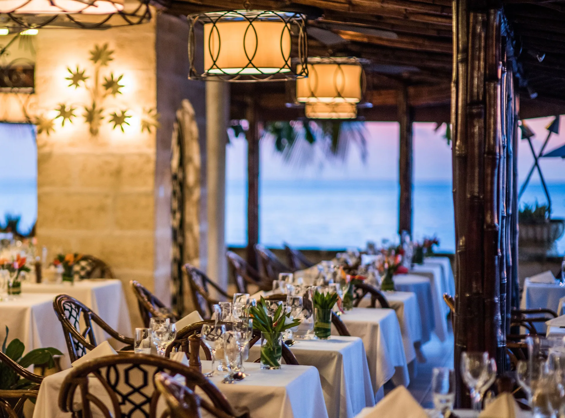 Oceanfront dining room with set tables and wicker chairs at Coral Reef Club.