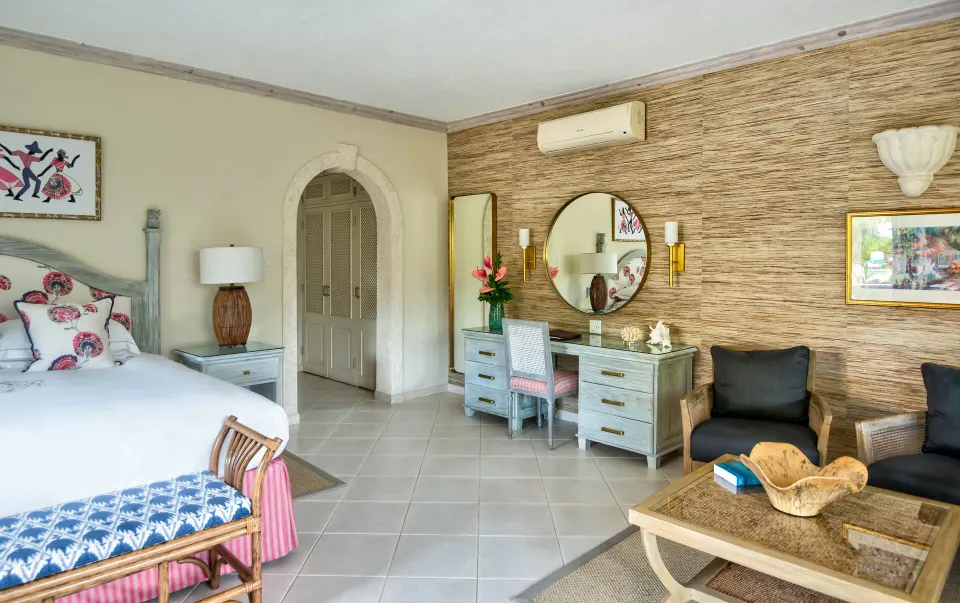 Junior Suite bedroom with bed, vanity and sitting chairs at Coral Reef Club.