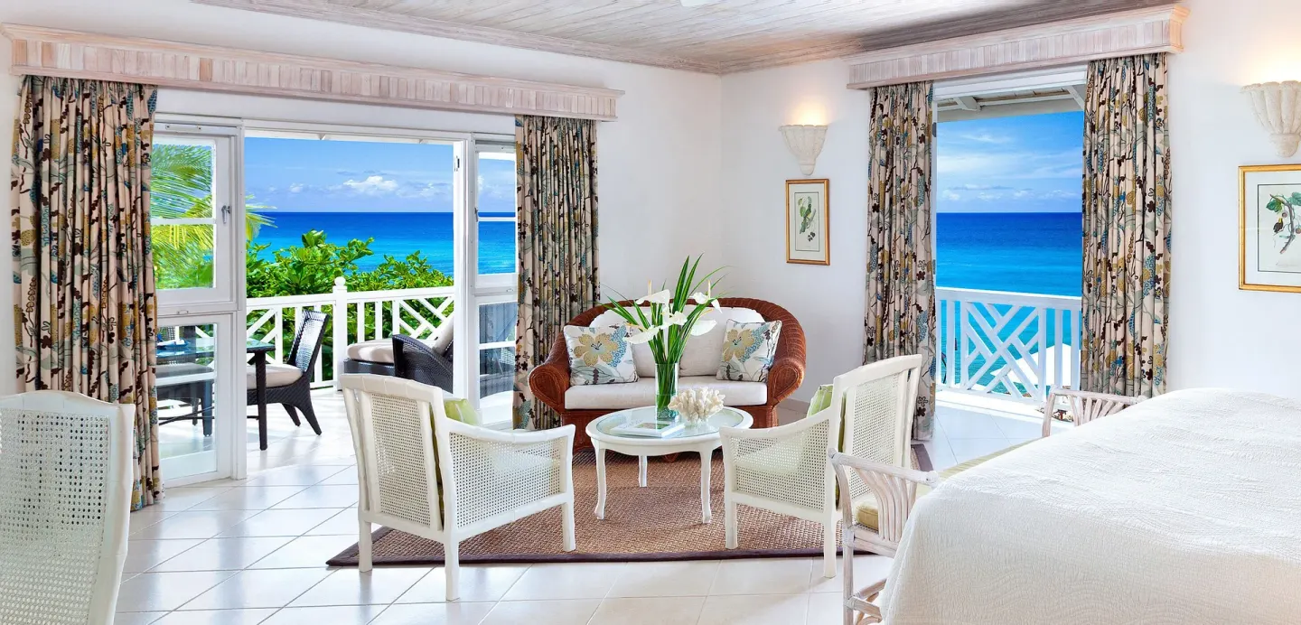 Junior Suite with white bed and ocean-facing balcony at Coral Reef Club.