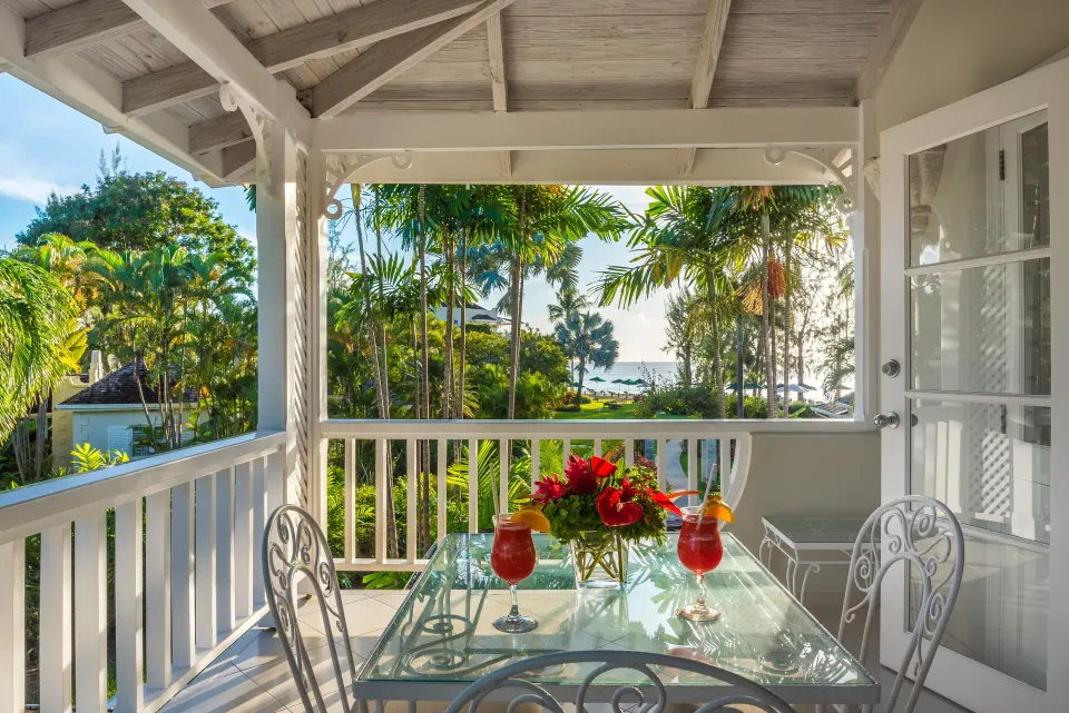 Luxury Cottage balcony with a table, drinks, gardens, and sea view at Coral Reef Club.