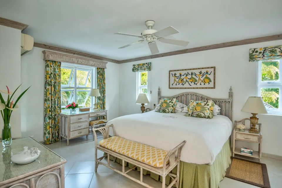 Luxury Cottage bedroom with a white bed and yellow floral fabrics at Coral Reef Club.