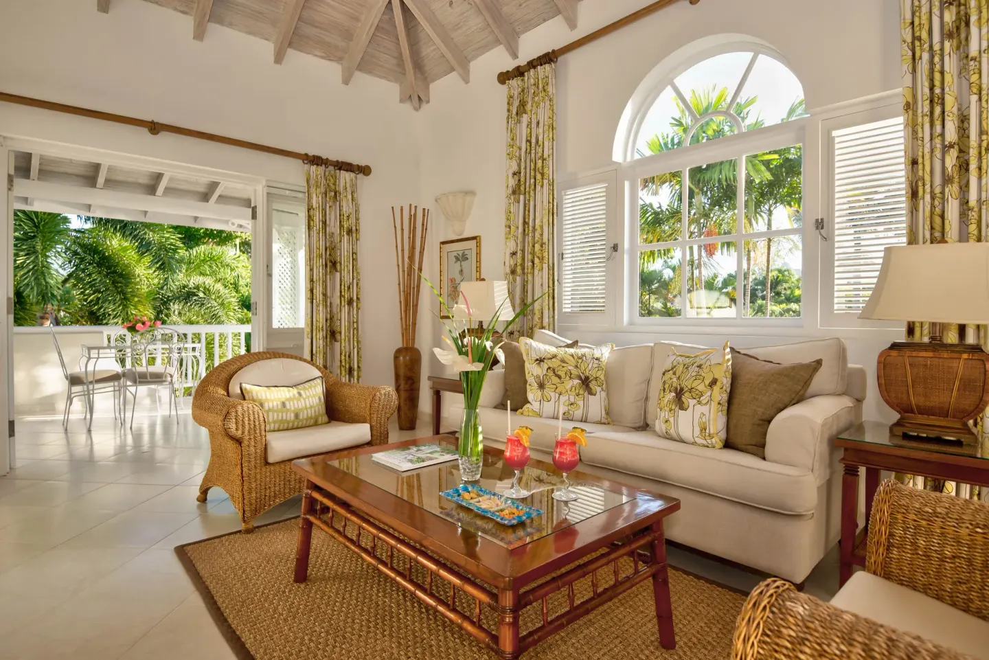 Luxury Cottage living room with wicker seating and terrace beyond at Coral Reef Club.