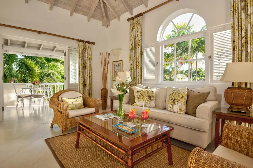 Luxury Cottage living room with wicker seating and terrace beyond at Coral Reef Club.