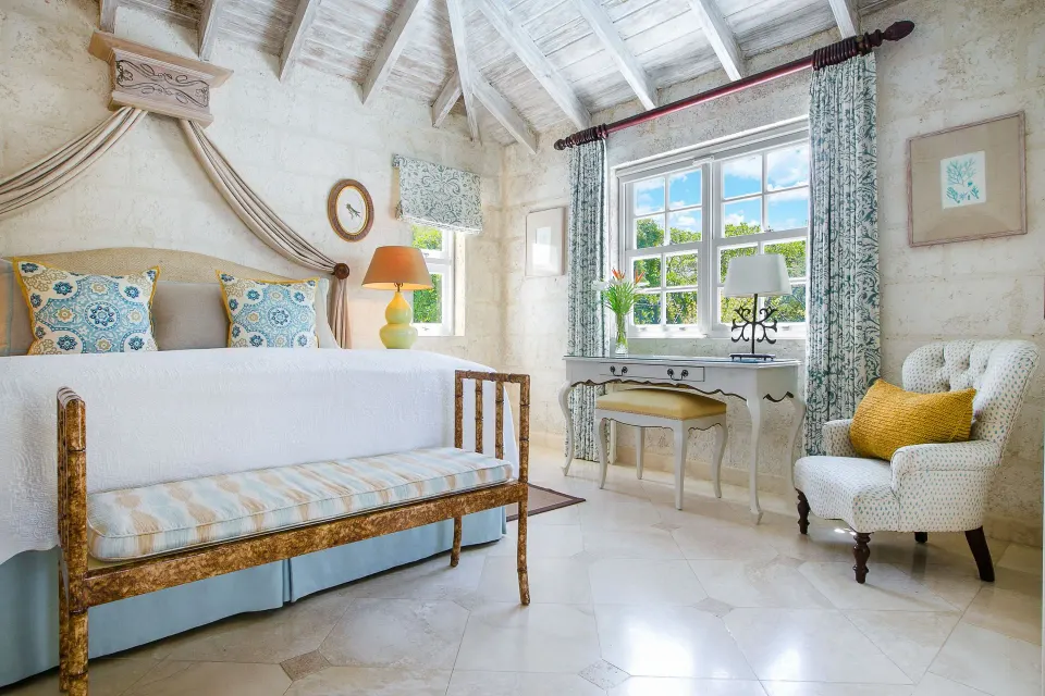 Luxury Suite bedroom with king bed, desk, armchair and vaulted ceiling at Coral Reef Club.