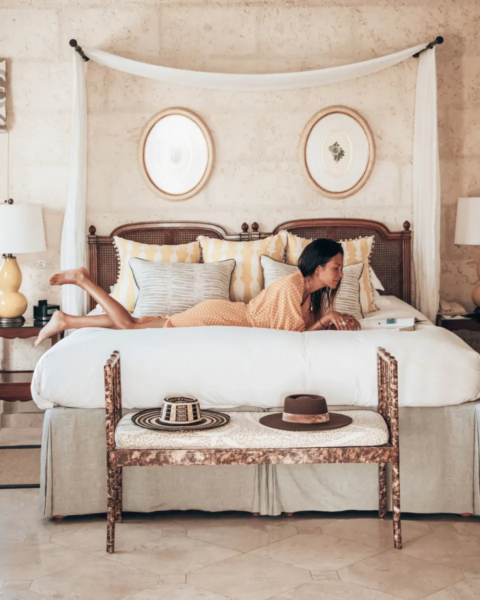 Luxury Suite king bed with canopy drape and bench at Coral Reef Club.