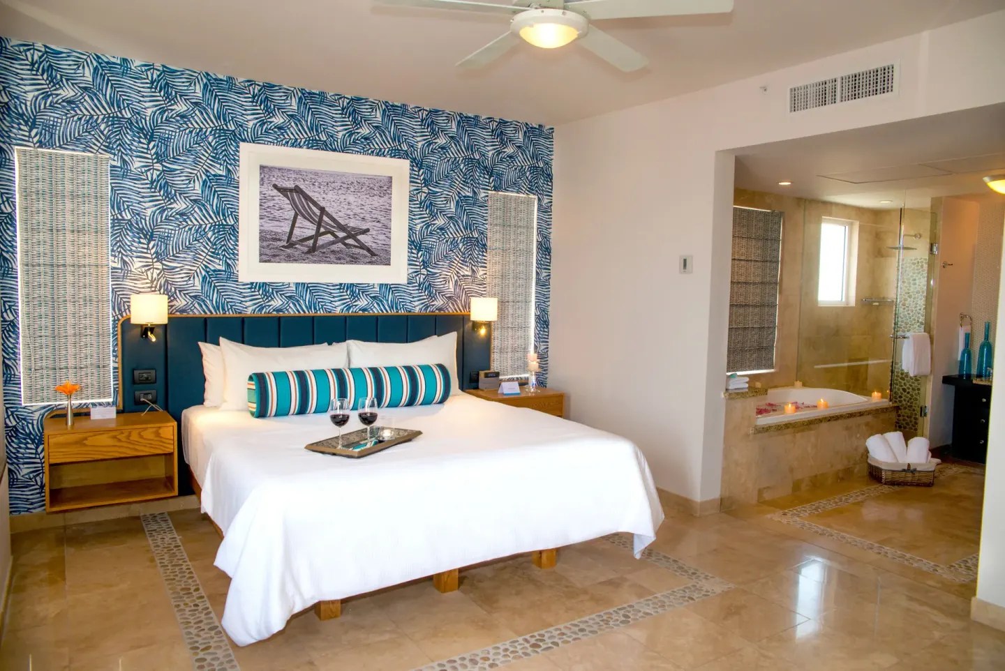 King bed guest room with leaf-pattern wall and open bath area at Corazón Cabo.