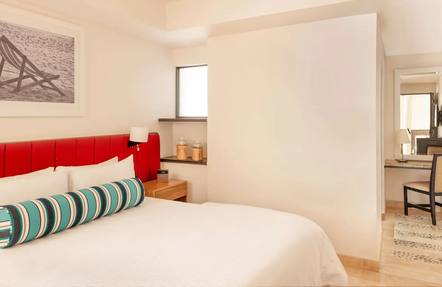 King bed with red headboard and adjoining vanity area at Corazón Cabo.