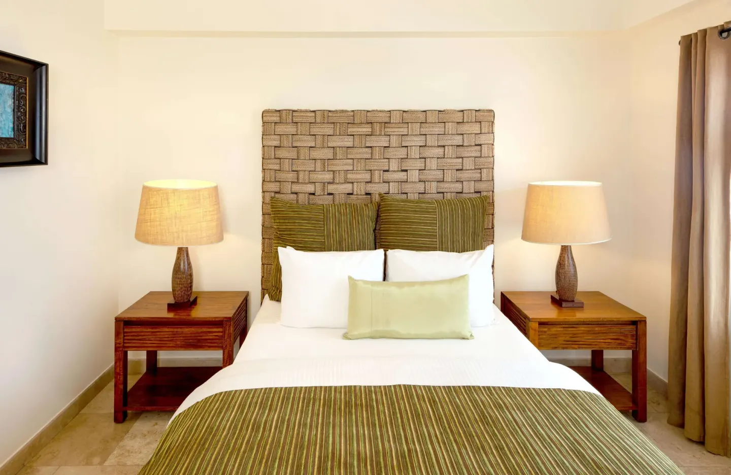 Guest room bed with woven headboard and bedside lamps at Corazón Cabo.