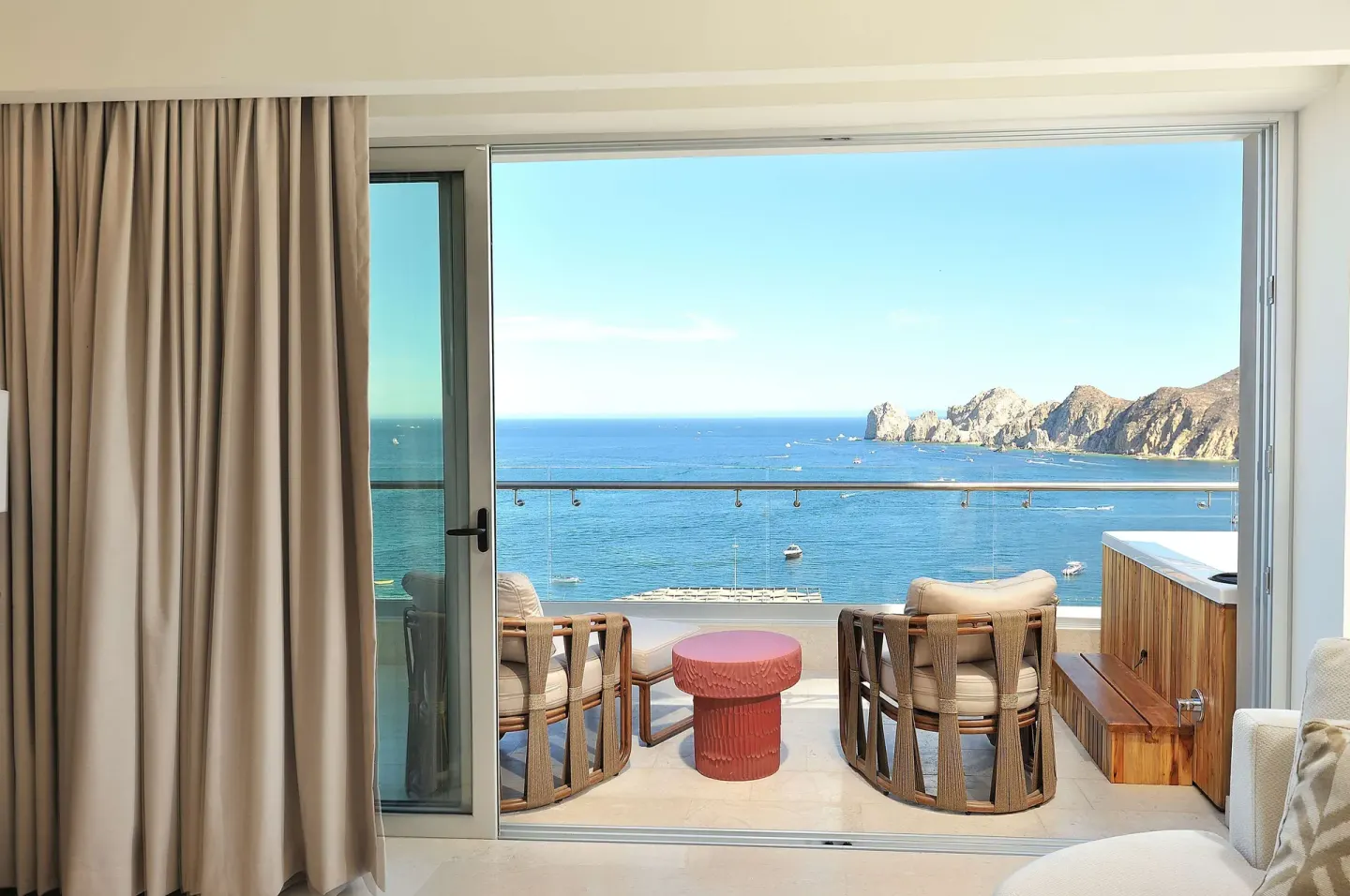 Ocean-view balcony at Corazón Cabo with lounge chairs and Land's End visible beyond the glass railing.