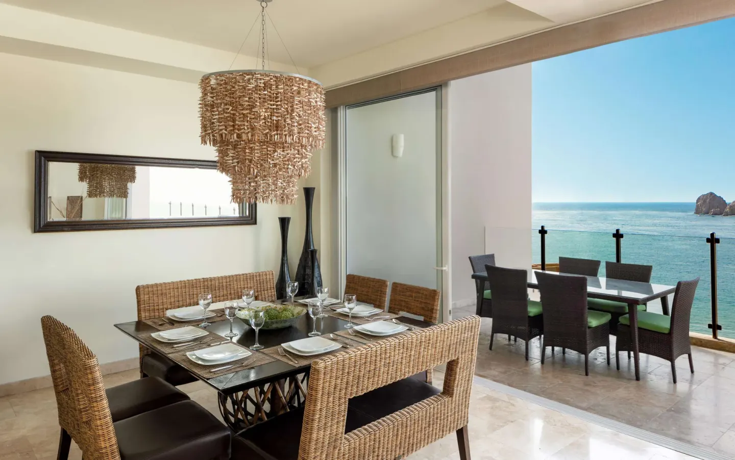 Dining table beside a balcony with ocean and rock formation views at Corazón Cabo.