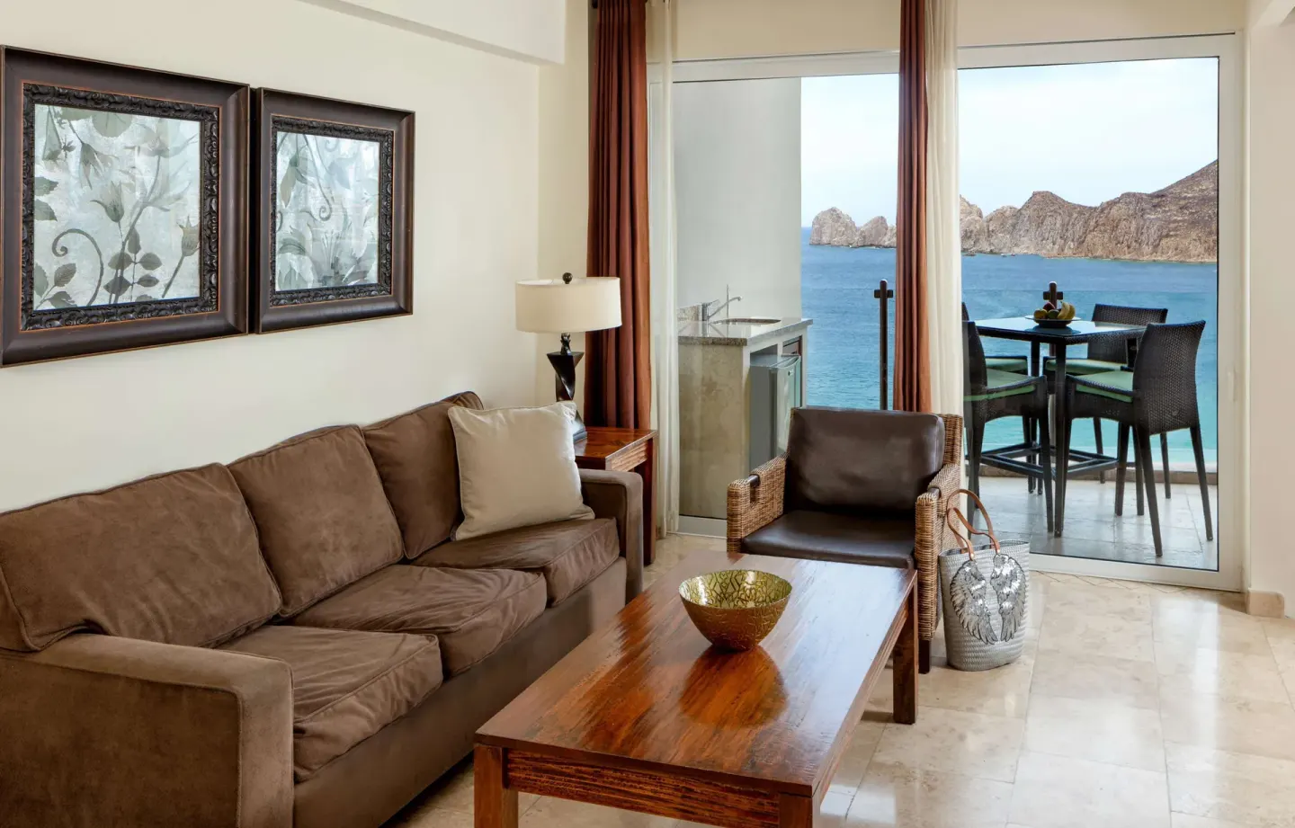 Suite sitting area with sofa, coffee table, and ocean-view balcony at Corazón Cabo.