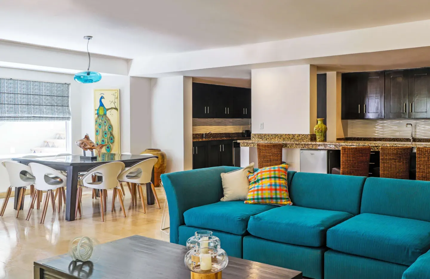 Living and dining area in a suite at Corazón Cabo with a turquoise sofa and open kitchen.