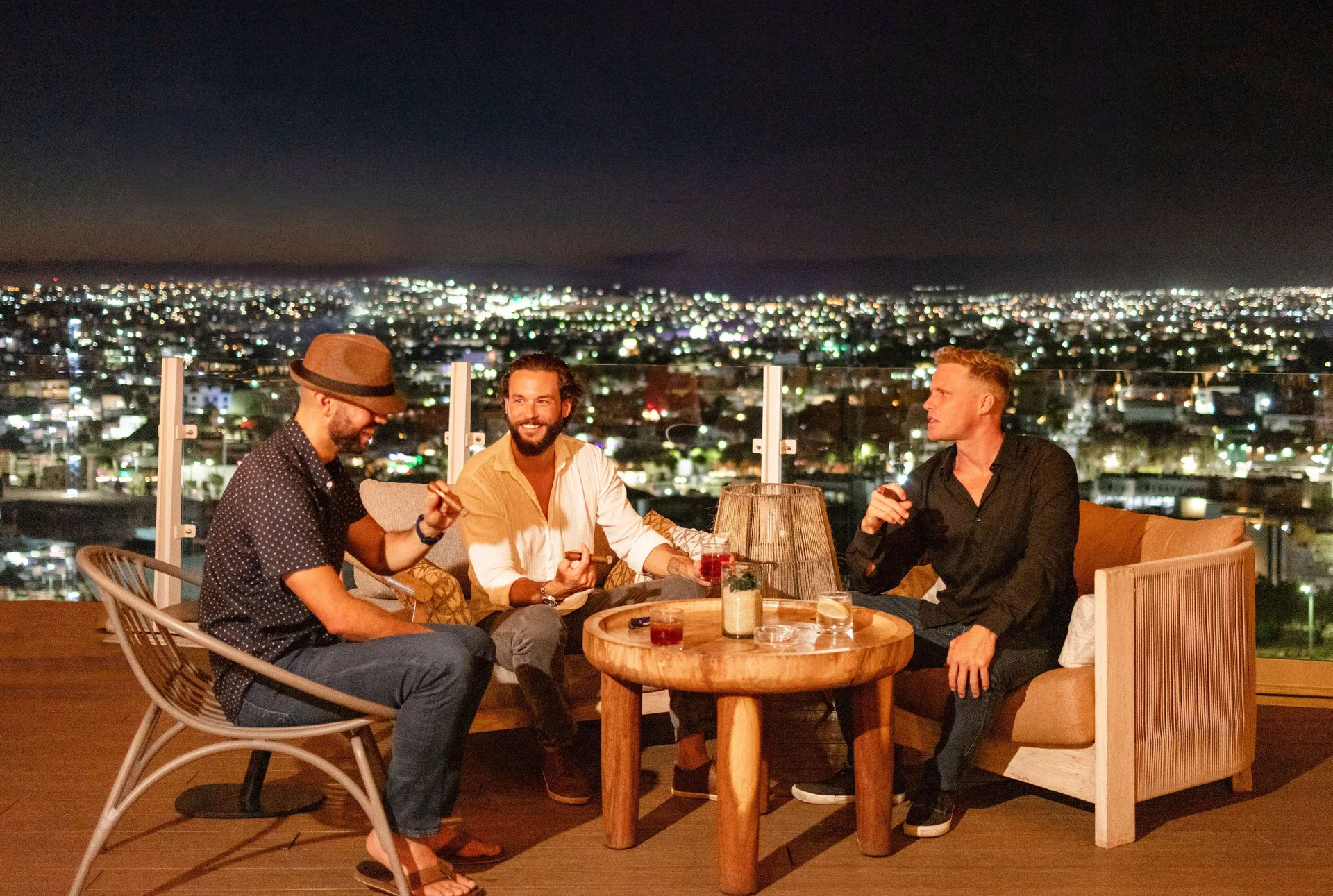 Guests sit with drinks on a nighttime rooftop terrace at Corazón Cabo.
