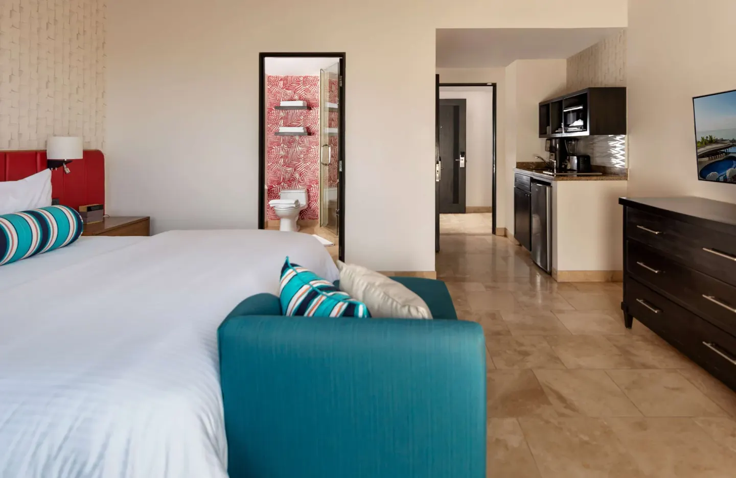 One Bedroom Deluxe king bed with sofa, kitchenette, and bathroom at Corazón Cabo.