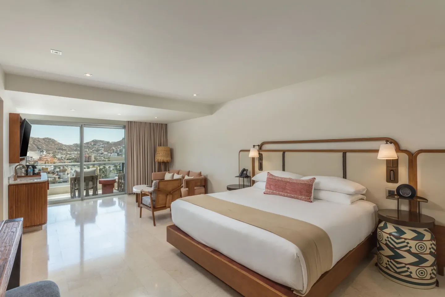 Infinity Sunset View room with king bed, lounge chairs, and balcony view at Corazón Cabo.