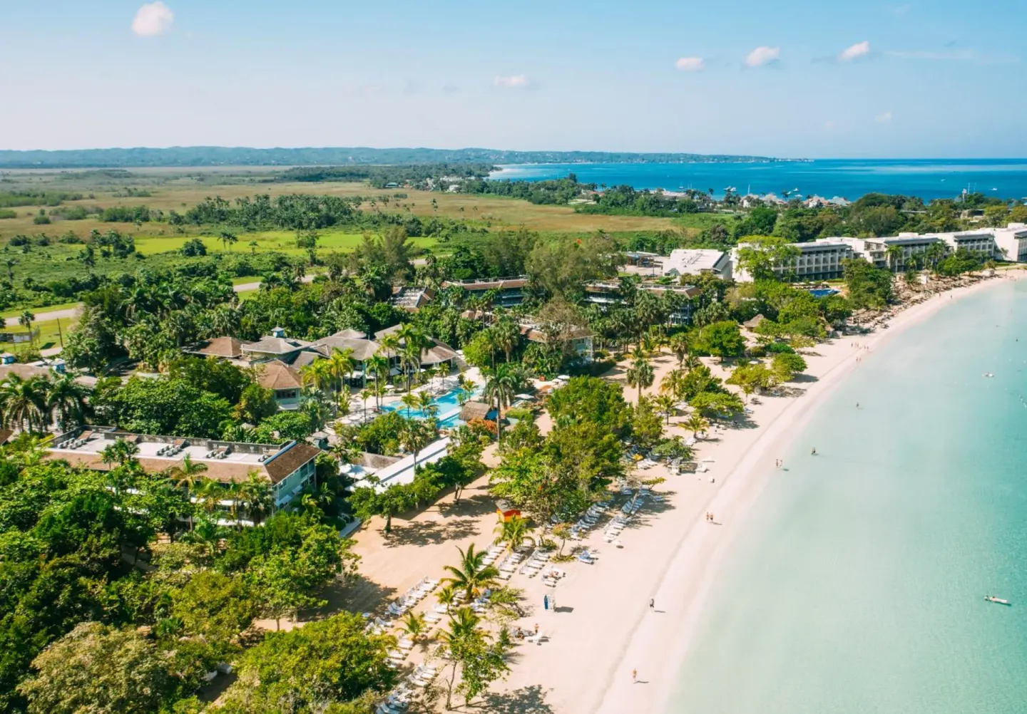 Aerial view of the beachfront, palms, and resort buildings at Couples Negril.