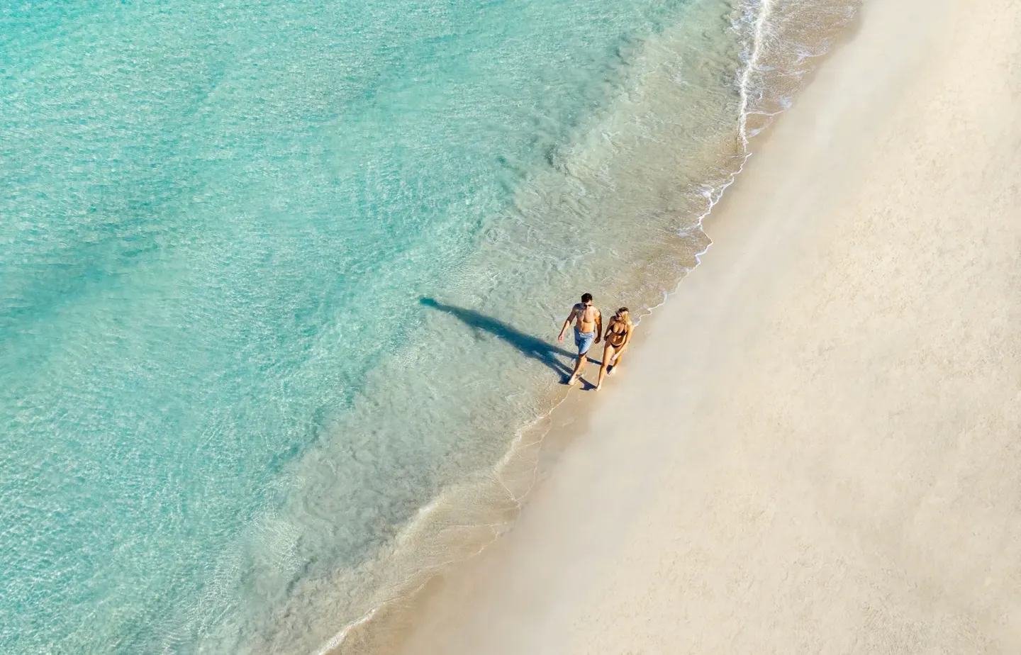 Aerial view of a couple walking along the turquoise shoreline at Couples Negril.