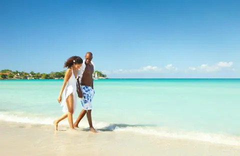 Couple walking along the shoreline in turquoise water at Couples Negril.