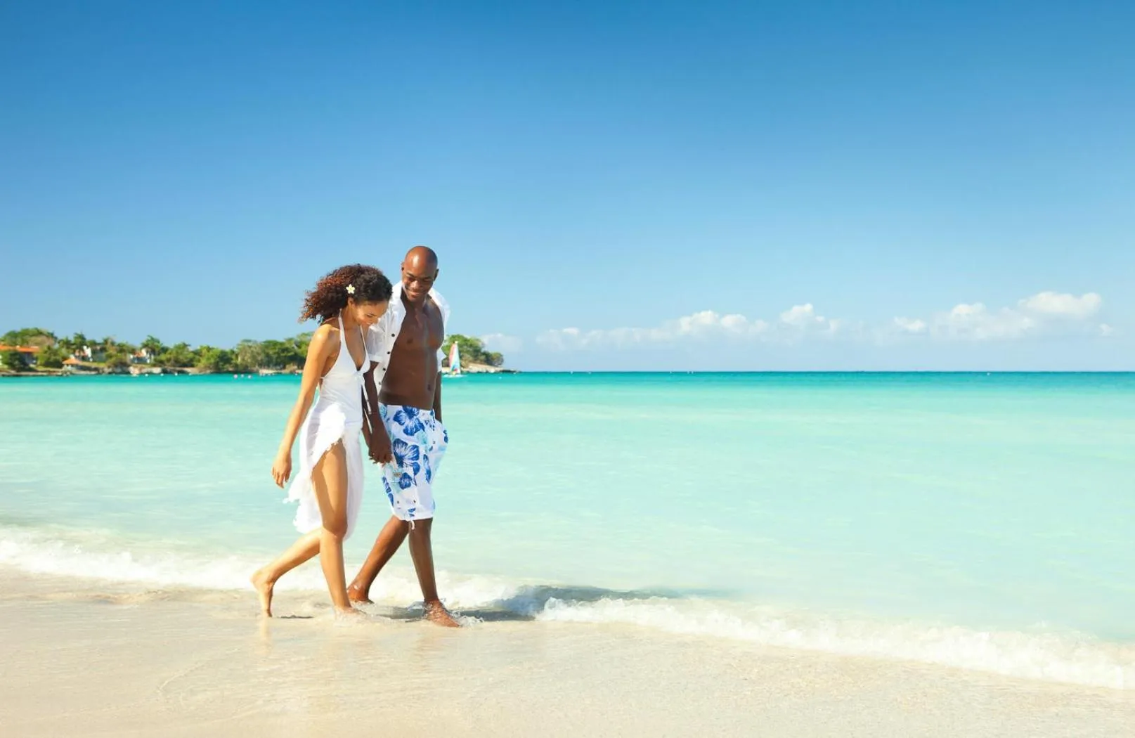 Couple walking along the shoreline in turquoise water at Couples Negril.