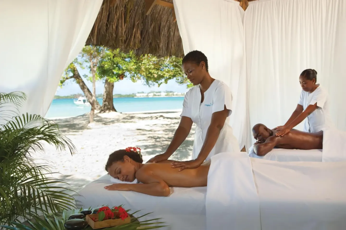 Beachside spa massage under a curtained thatched cabana at Couples Negril.