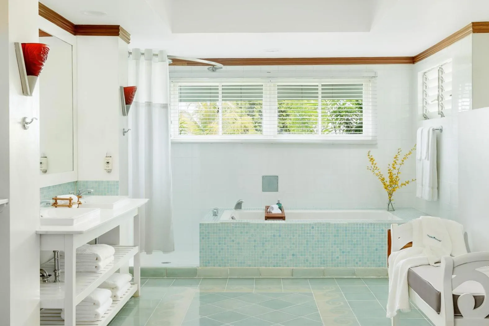 Bright bathroom with tub, shower, vanity, and lounge chair at Couples Negril.