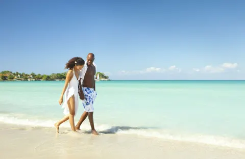 A couple walks along the shallow turquoise shoreline at Couples Negril.