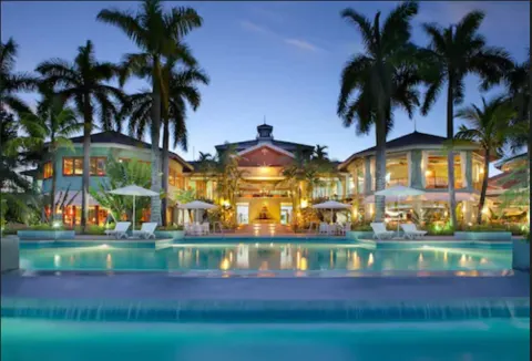 Evening pool view with palm trees and illuminated resort buildings at Couples Negril.