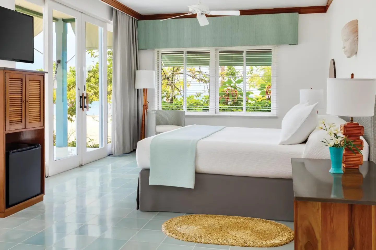 Guest room with king bed, windows, and balcony doors at Couples Negril.