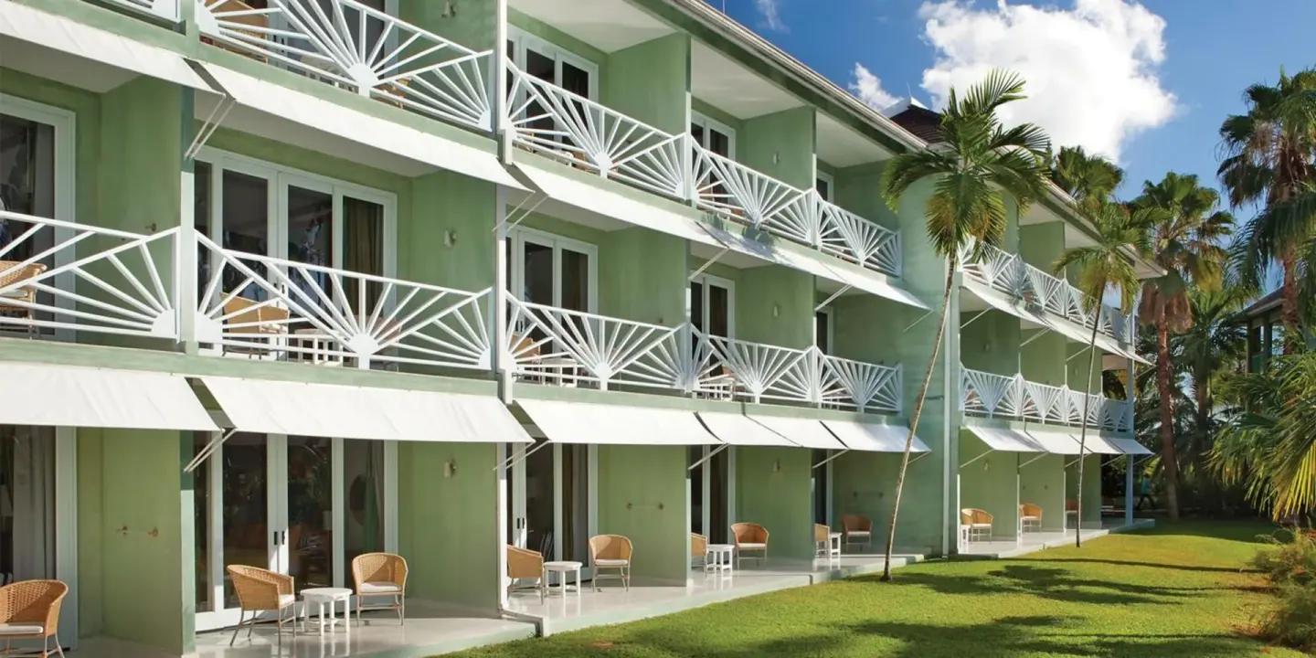 Green guest room building with white balconies and lawn at Couples Negril.