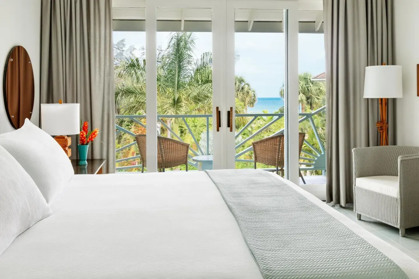 Guest room bed with balcony seating and ocean glimpses at Couples Negril.