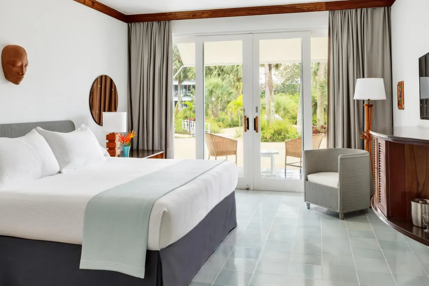 Guest room with a king bed and patio doors facing tropical landscaping at Couples Negril.