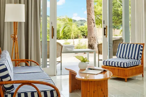 Guest room sitting area with striped chairs and patio doors at Couples Negril.