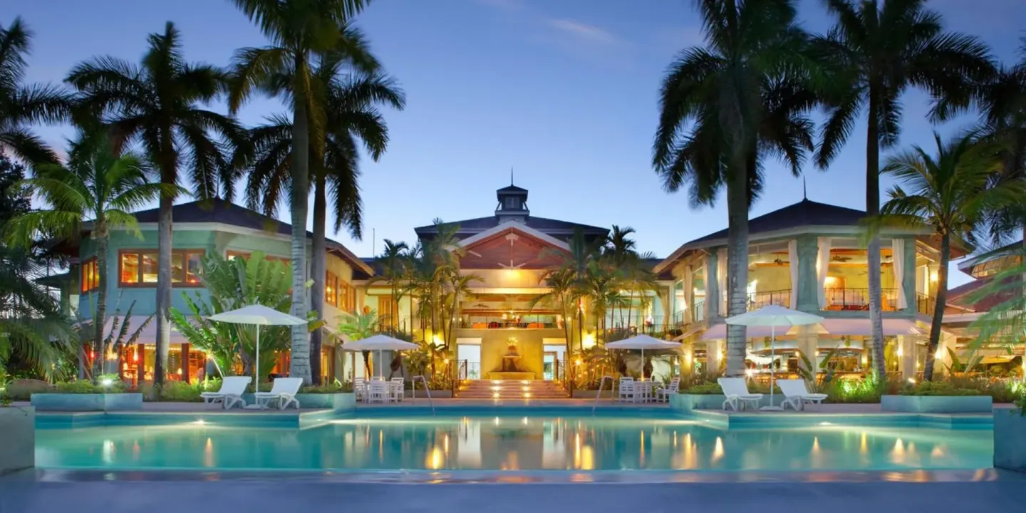 Twilight view of the illuminated main pool and resort buildings at Couples Negril.