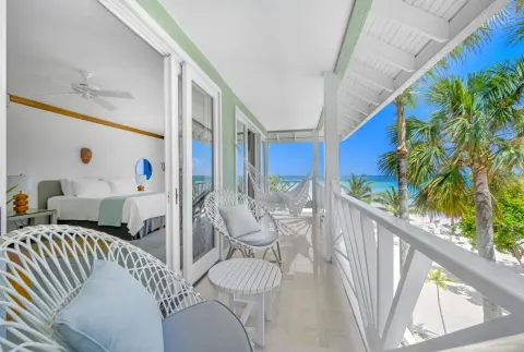 Ocean-facing balcony with white chairs and a hammock at Couples Negril.