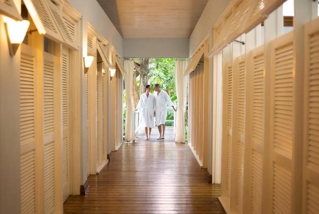 Guests in robes walk along a louvered spa corridor at Couples Negril.