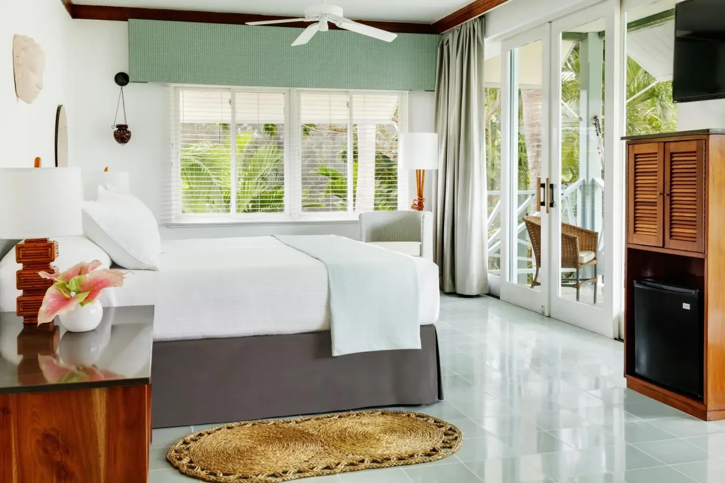Garden Suite room with a white bed, louvered cabinet, and glass balcony doors at Couples Negril.