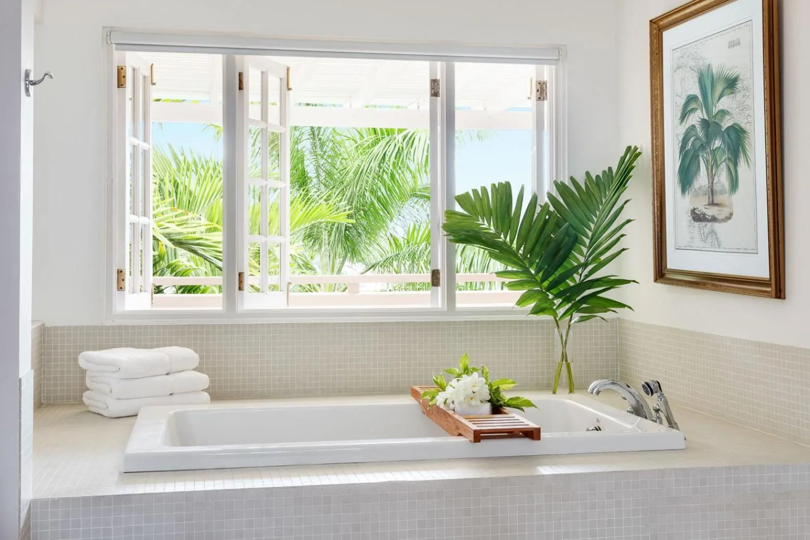 Bright bathroom soaking tub with open windows and palm leaves at Couples Sans Souci.