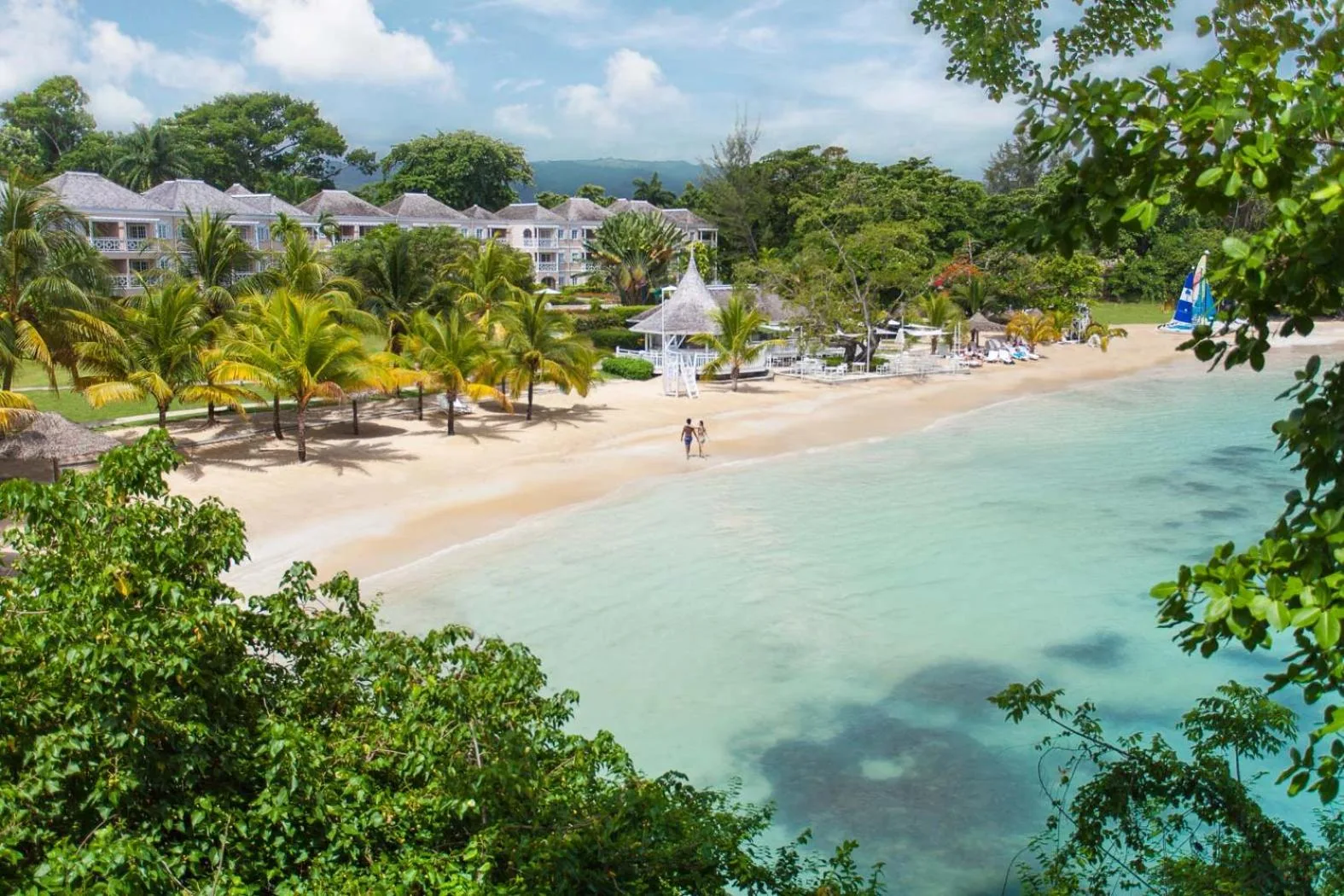 Aerial view of the beach, palms, and turquoise bay at Couples Sans Souci.