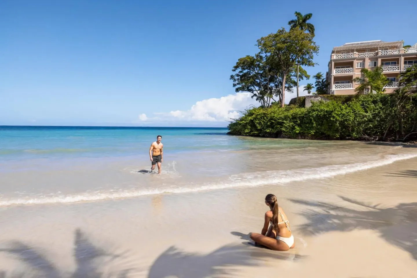 Guests relaxing on the sandy beach and in shallow water at Couples Sans Souci.