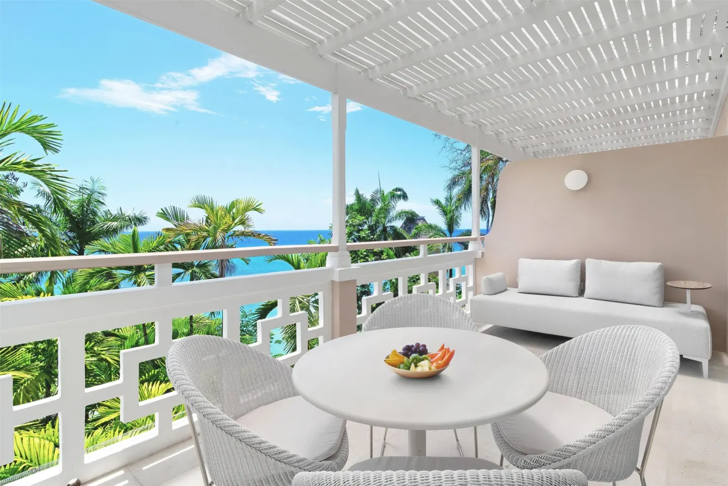 White furnished balcony with palms and ocean beyond at Couples Sans Souci.