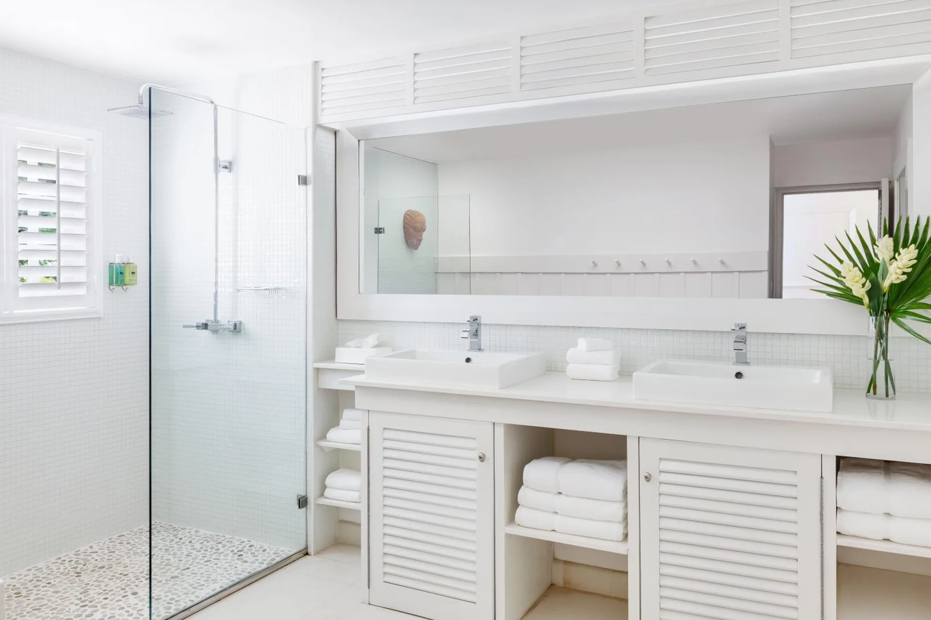 White guest bathroom with double sinks and glass shower at Couples Sans Souci.