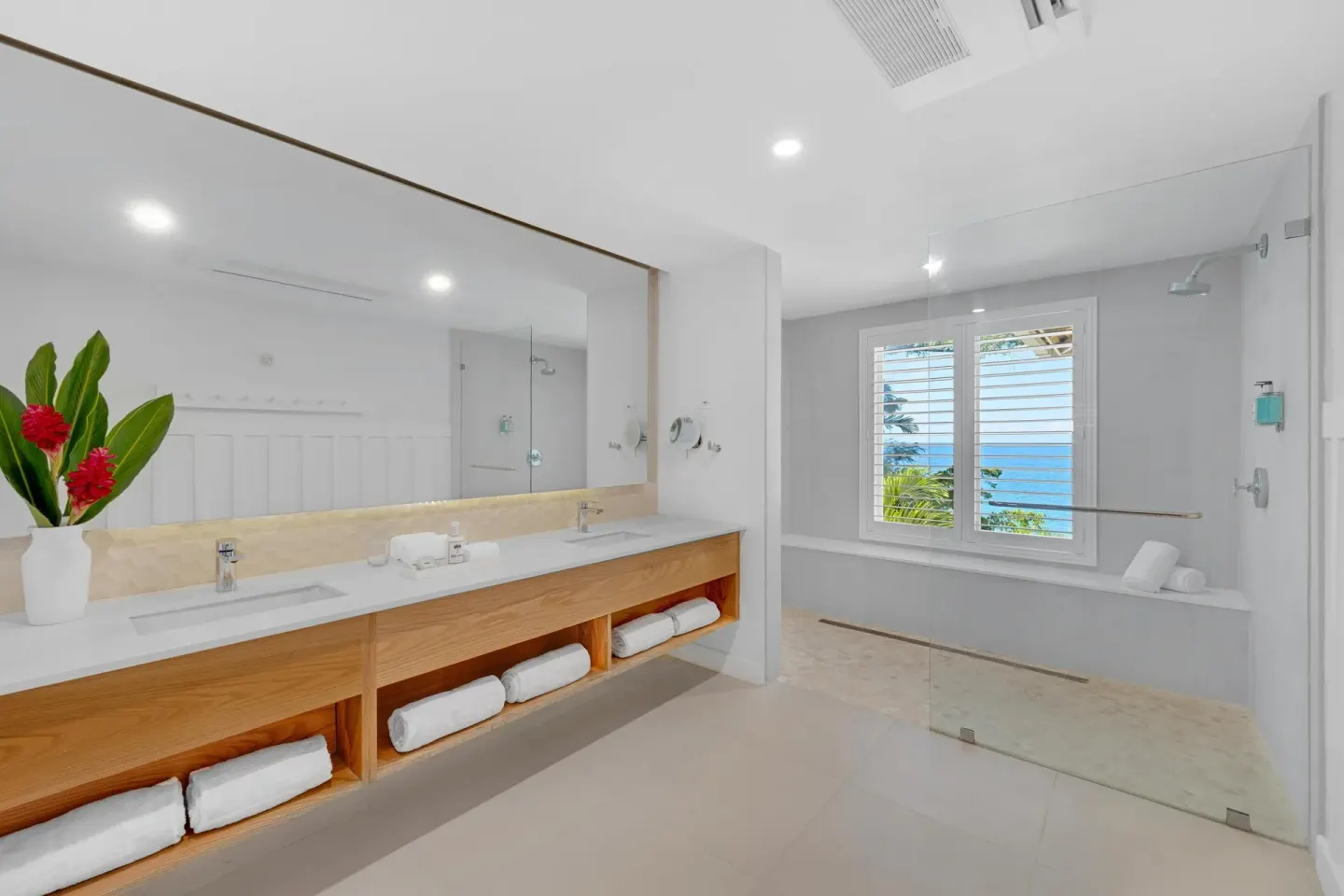 Bright bathroom with double vanity and ocean-view window at Couples Sans Souci.