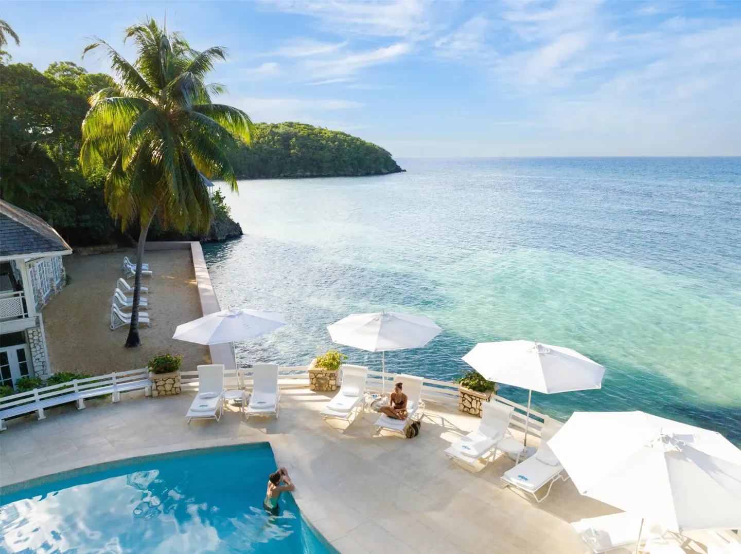 Pool terrace with white loungers overlooking the Caribbean Sea at Couples Sans Souci.
